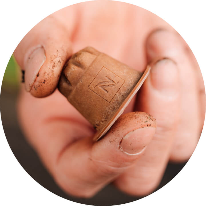 Nespresso Home Compostable Original coffee capsule in the hand of a coffee farmer